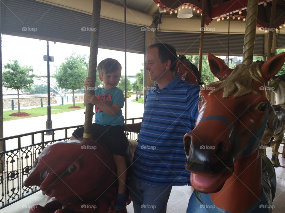 Father and son having fun on a carousel 