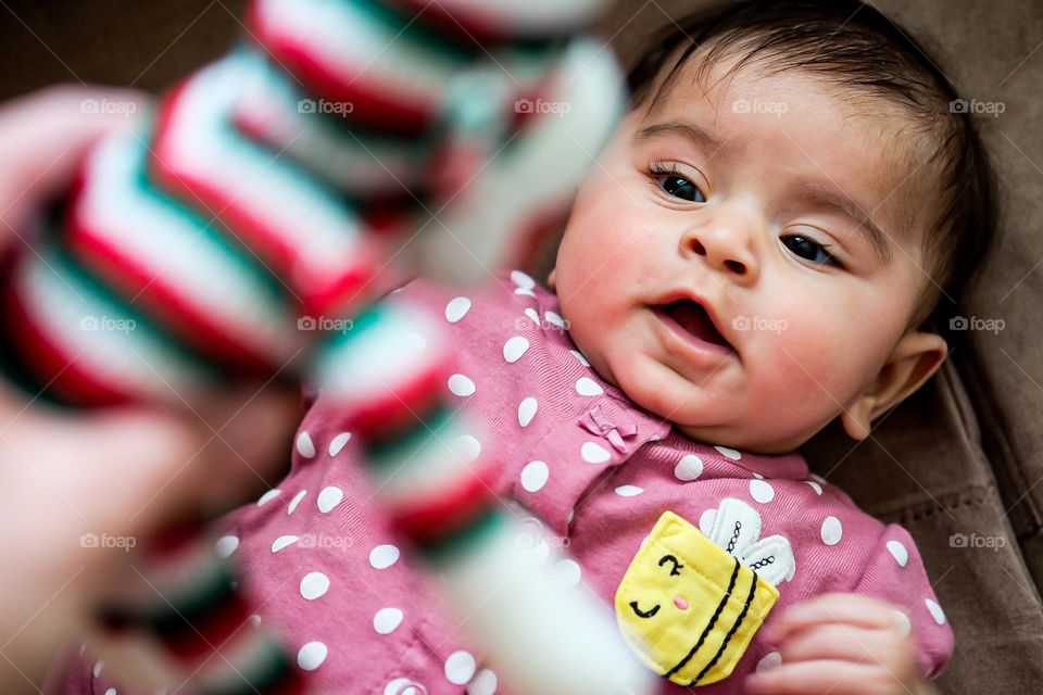 Baby surprised at stuffed monkey toy, baby expression of surprise, baby with mouth open, baby loves monkey toy, surprising baby with a toy, striped monkey toy and baby