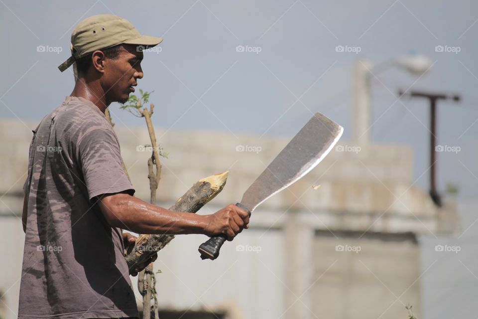 Cane Machete. Cuban farmer sharpening a wooden stick end with a cane machete/mocha