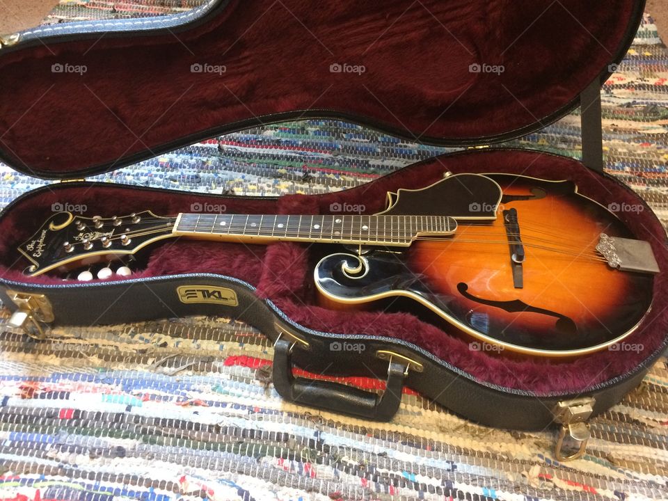 Mandolin in case on colorful rug. 