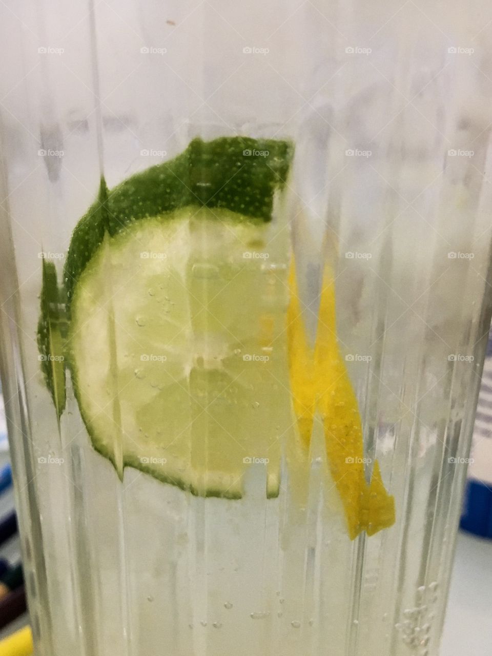 The slice of lemon and lime in the glass of lemonade. Cold beverages background.