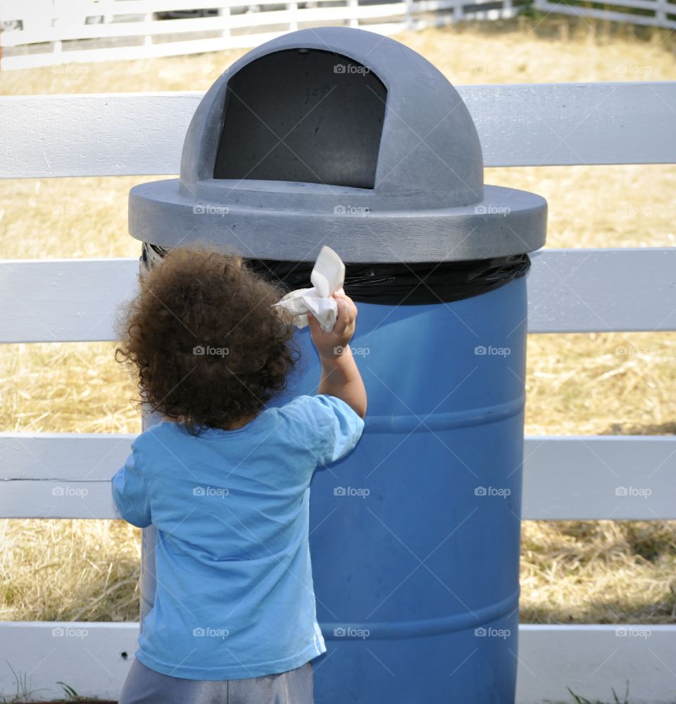 Boy throwing garbage into trash can.