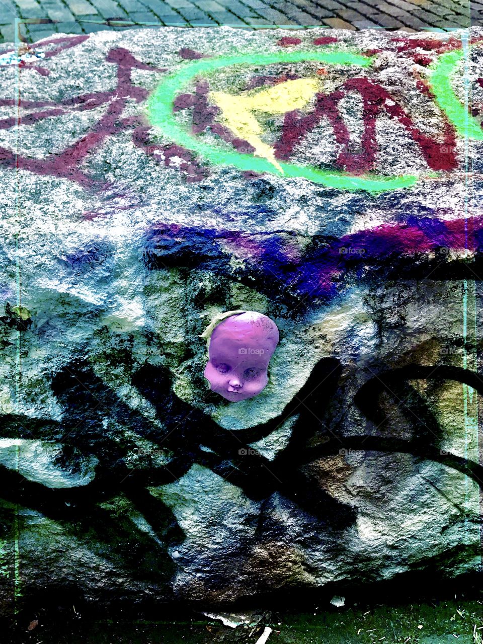 Graffiti on rock and creepy Doll face, sidewalk art in SOHO, New York City 