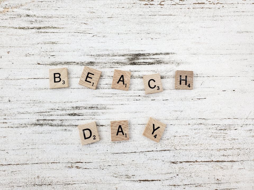 Square wooden word have a beach day and seashells on a rustic white background 