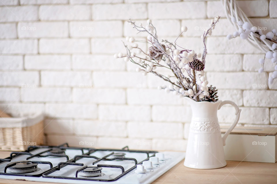 Festive winter cozy kitchen interior with garlands, decorations and gifts.  Christmas dinner at the decorated table.