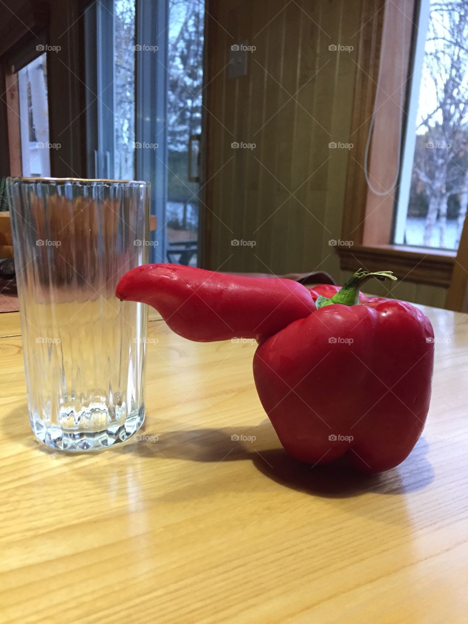 Penis red sweet pepper on a table with a glass