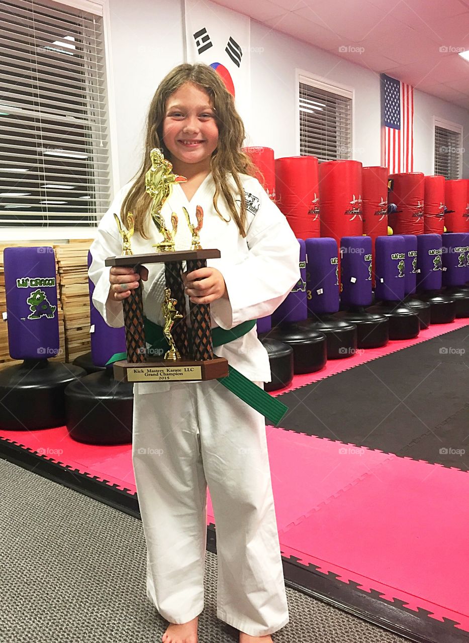 Portrait of a girl holding karate trophy