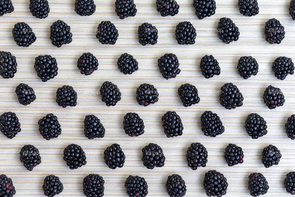 Flatlay of blackberries on wooden background symmetrically arranged