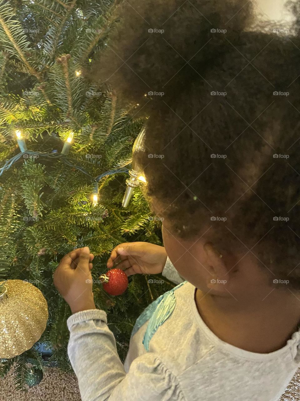Girl hangs ornament on tree