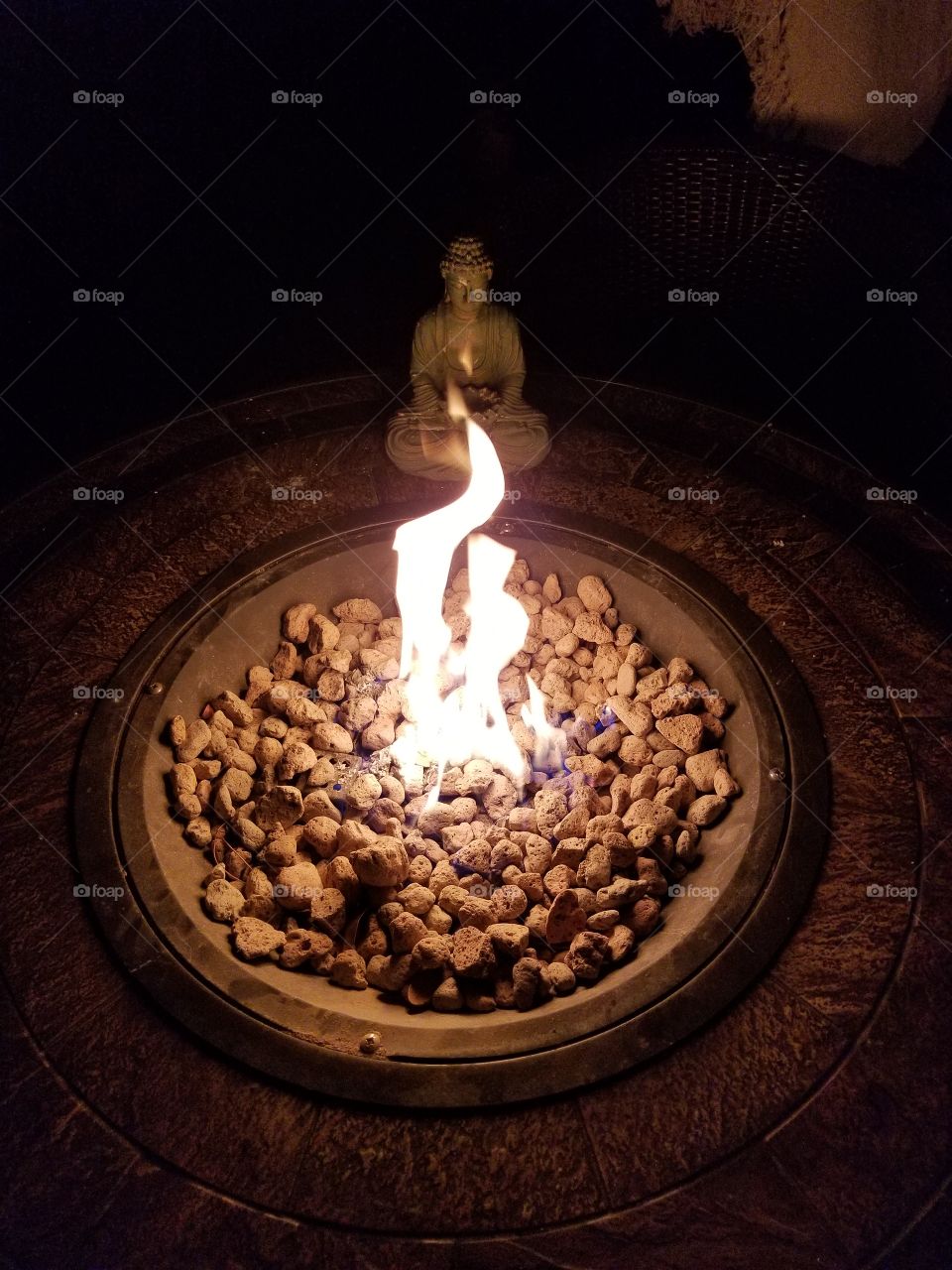 Buddha by the fire. small fire over a fire pit of coal. In the Darkness outside the fire gives a tranquil feeling.