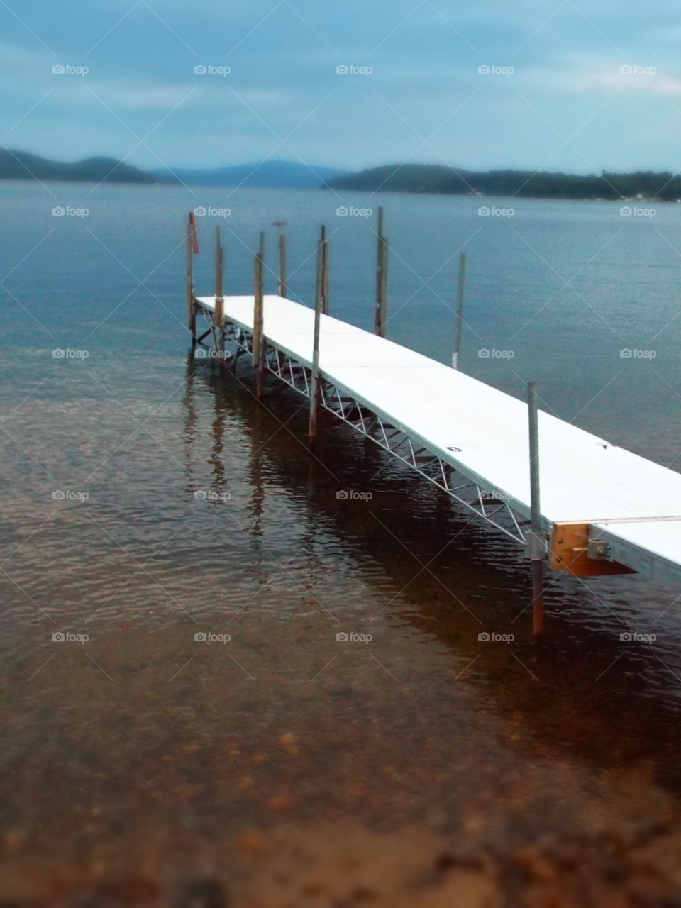 White metal boat pier extending into lake on overcast day with blurred effect
