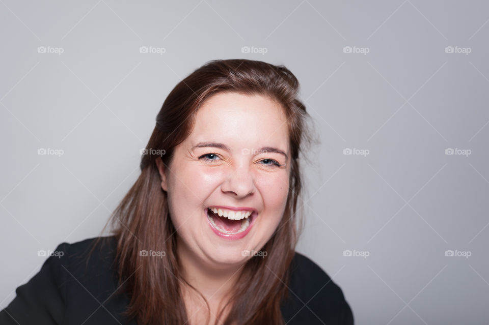 Studio portrait of happy young woman laughing.