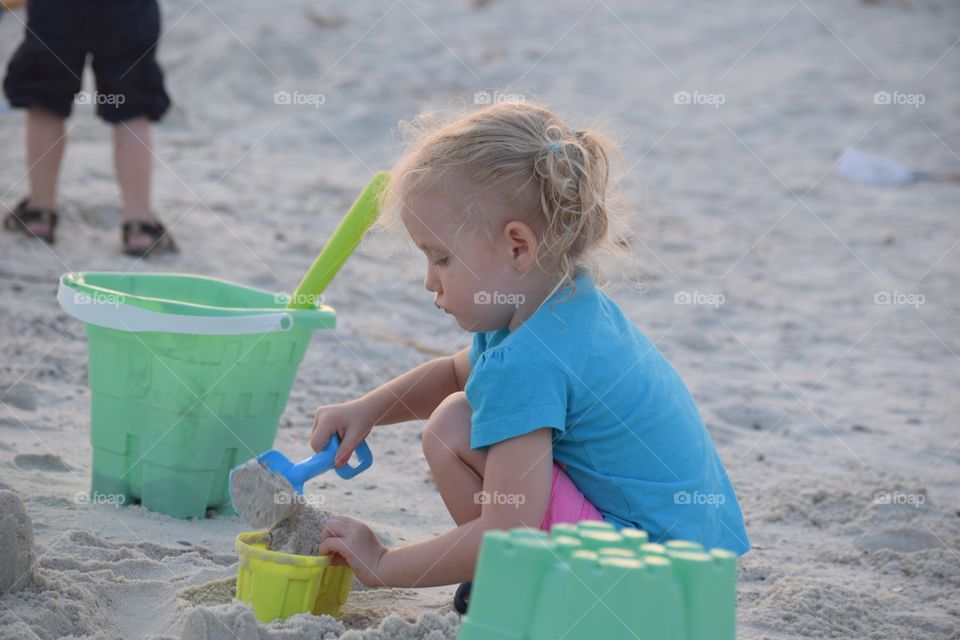 Girl digging in the sand . At the beach with buckets and shovels