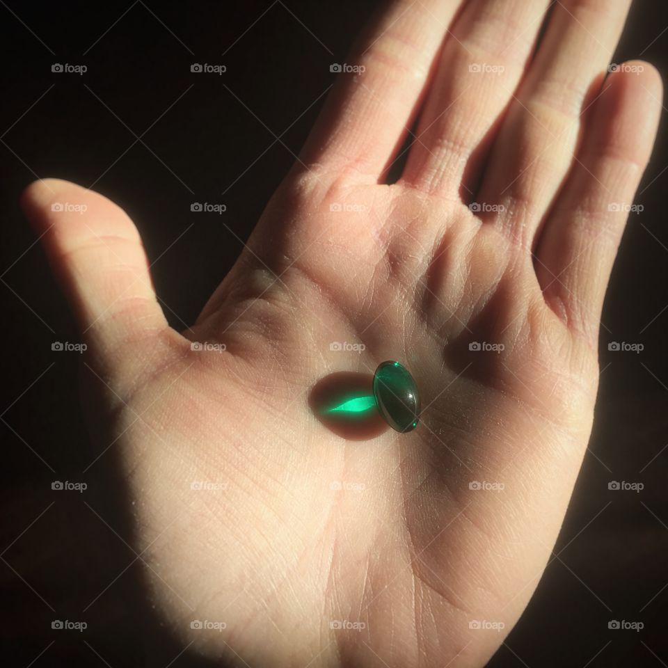 Green pill in the palm of a hand