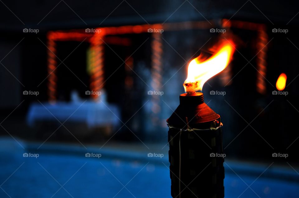 Pool party at night. Tiki torches are lit up for the party