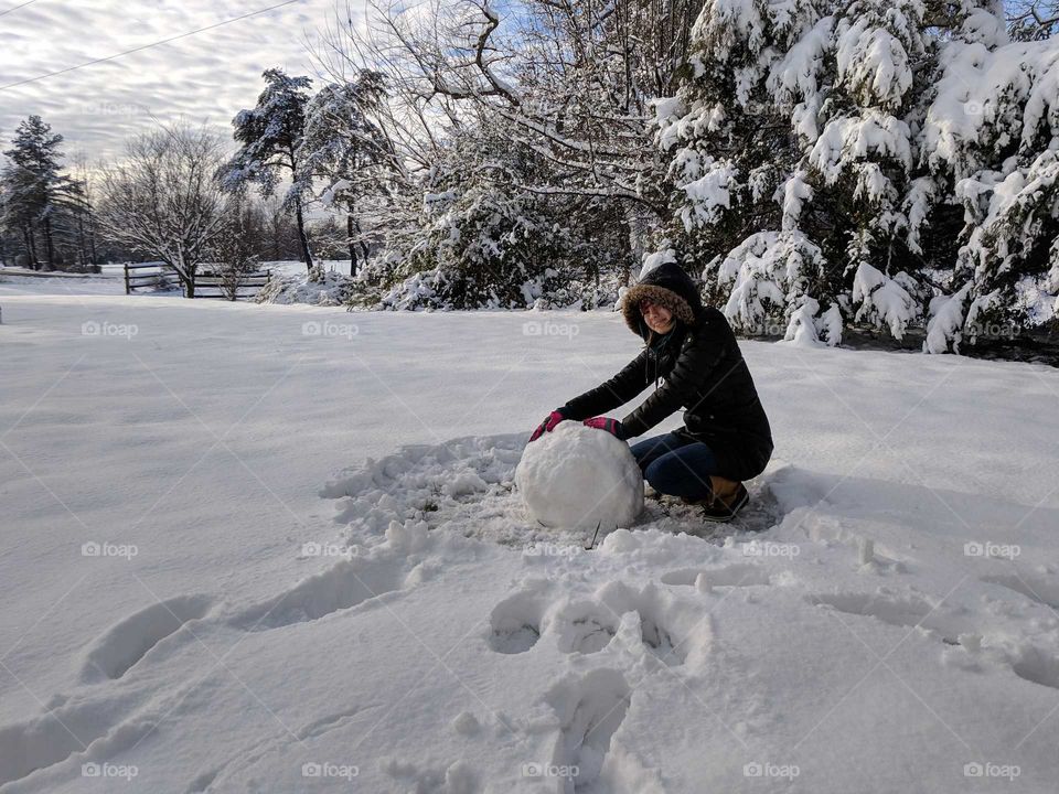 making a snowman in the front yard full of snow after the storm this weekend