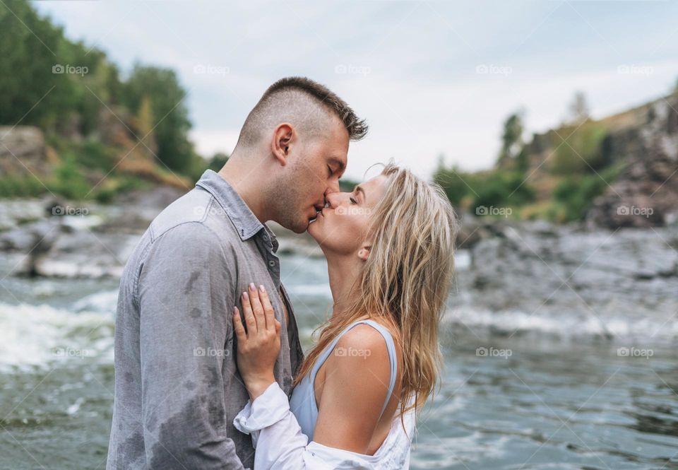 Happy young couple in love travelers kissing in mountain river