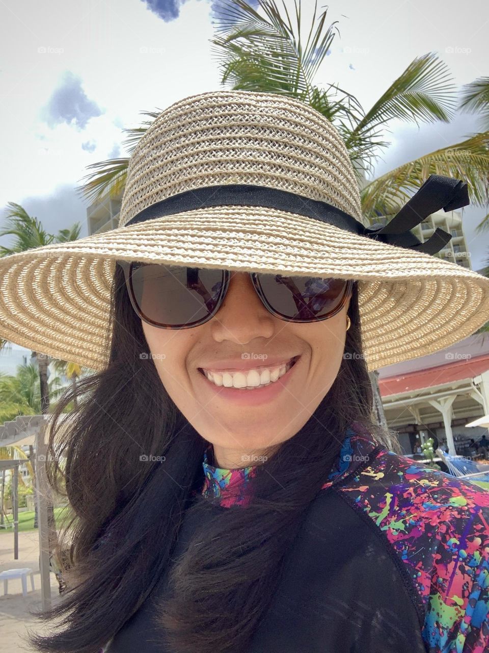 Selfie portrait of a woman wearing hat and sunglasses at tropical place San Juan Puerto Rico.