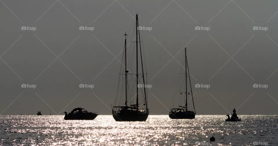 Sailing boats against the sunlight at the sunset 