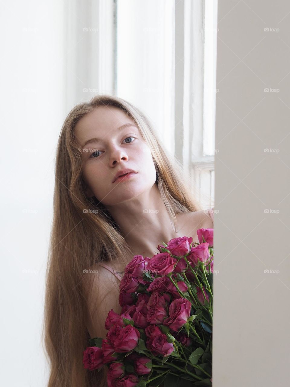 Young blonde beautiful girl with bouquet pink roses, looking at camera 