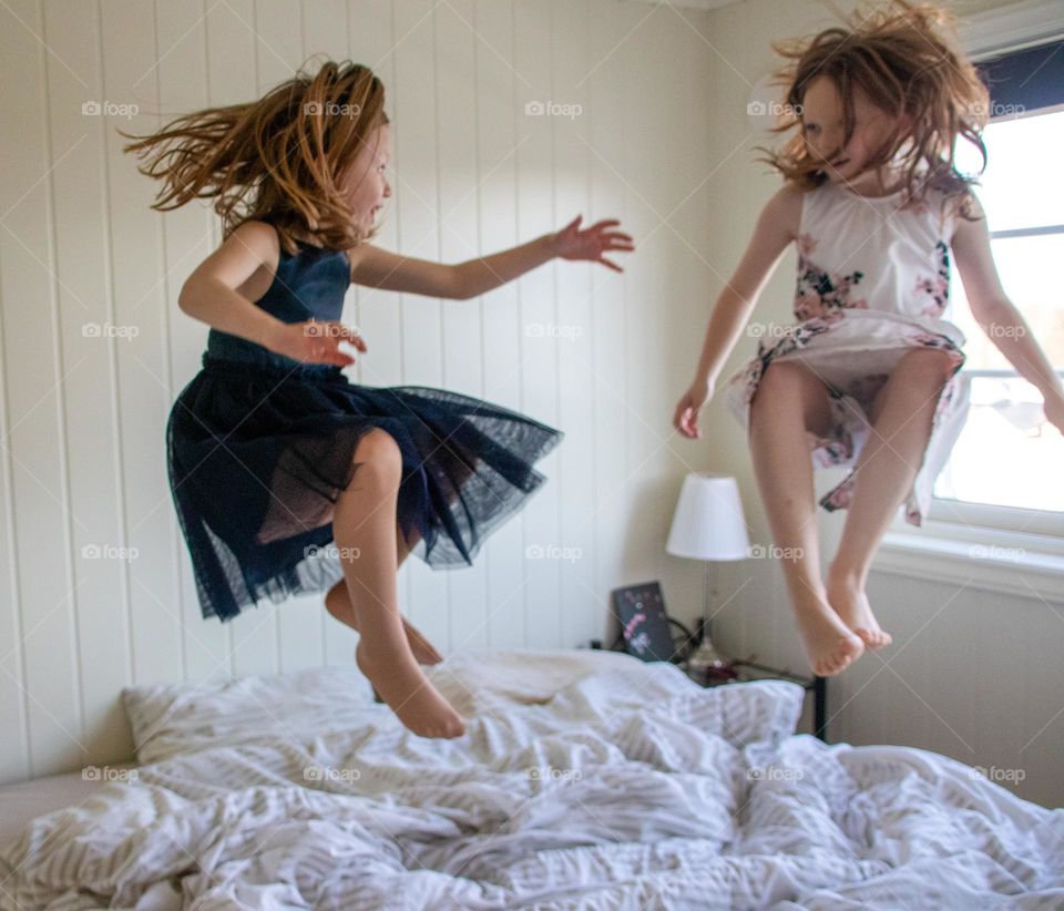 Two sisters jumping in the bed before they are going to bed .
They have a lot of fun when I suprize them.