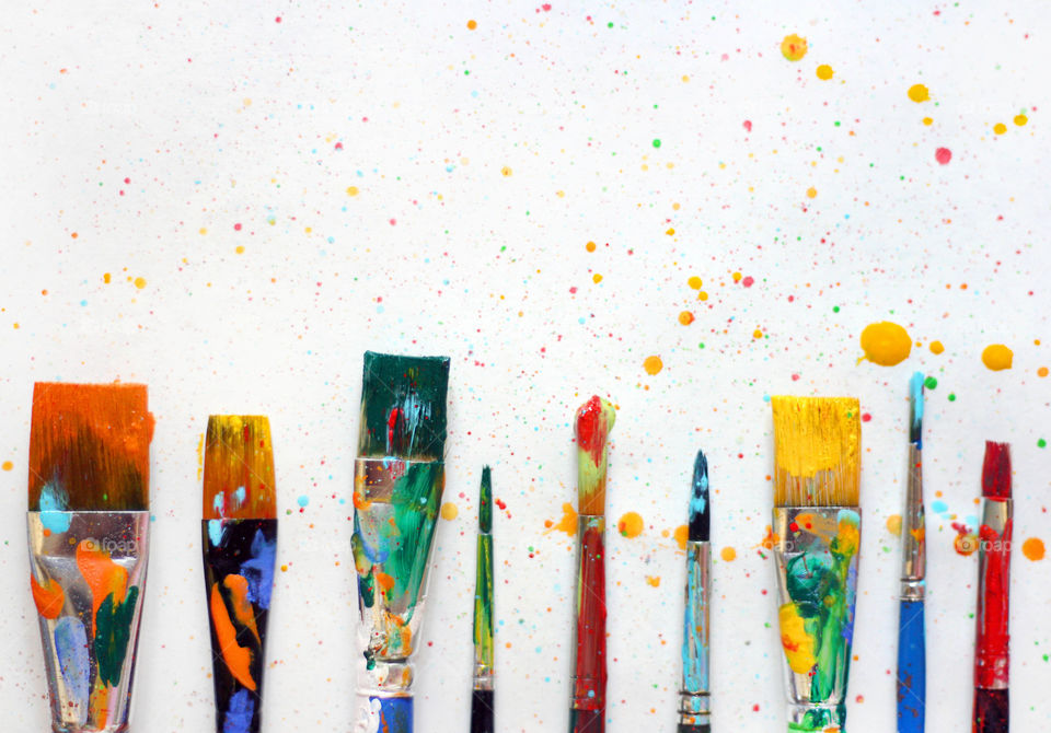 Colorful paintbrushes with paint spoted background, close up