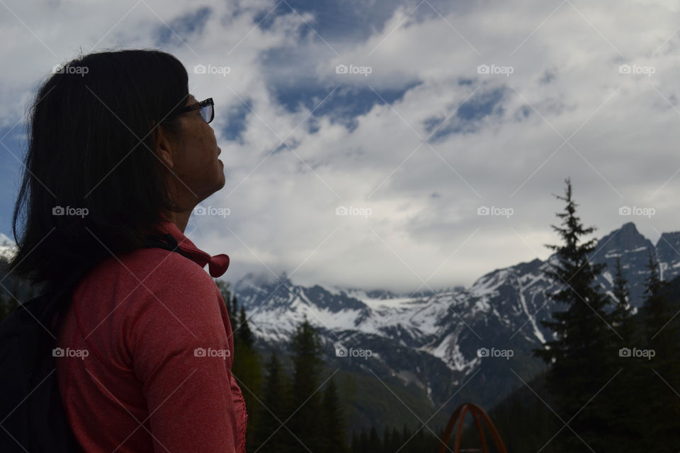 Side view Asian woman on overcast winter day looking at the snowy Canadian Rocky Mountain scenery 