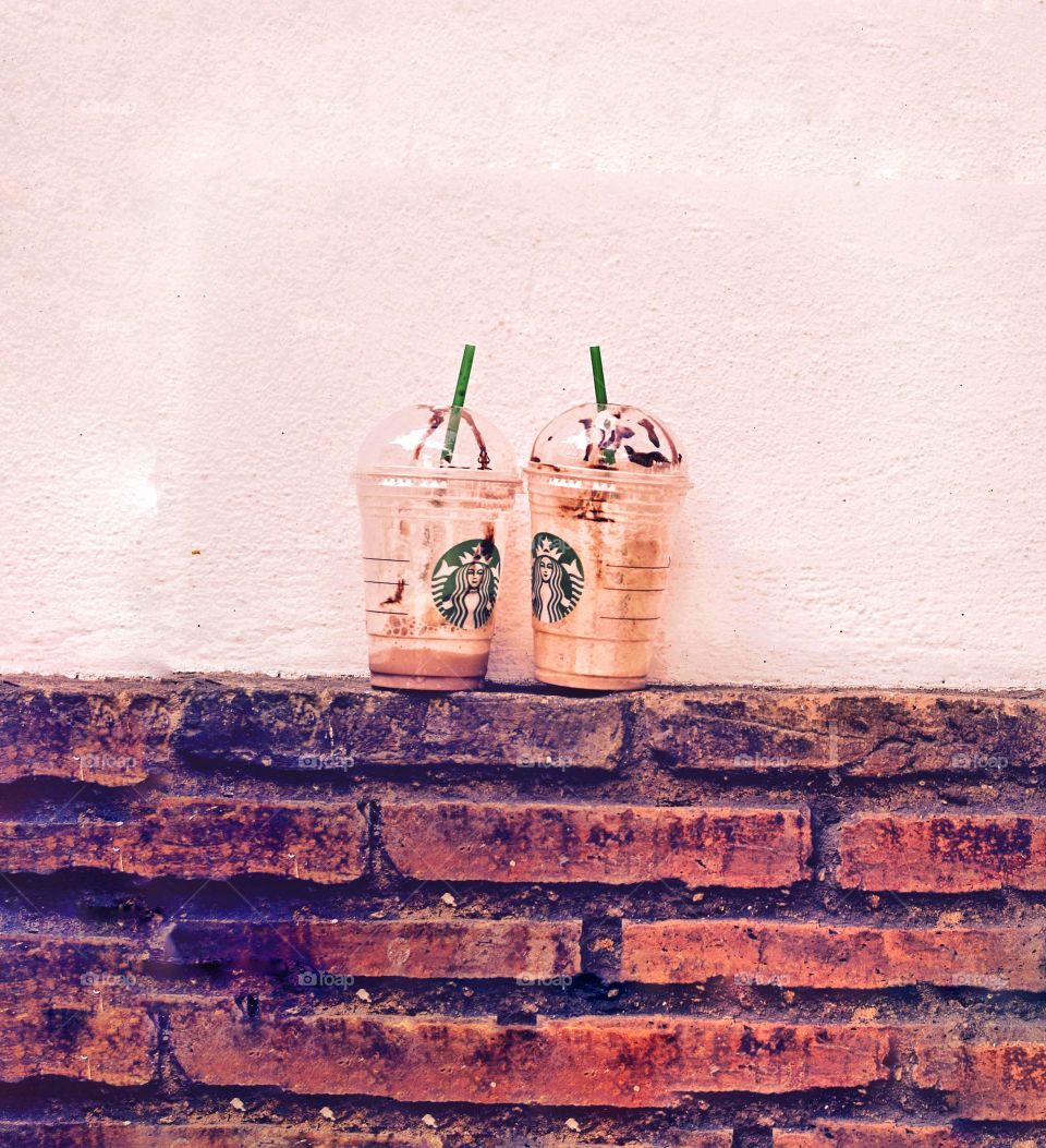 Duo Starbucks coffee on brick