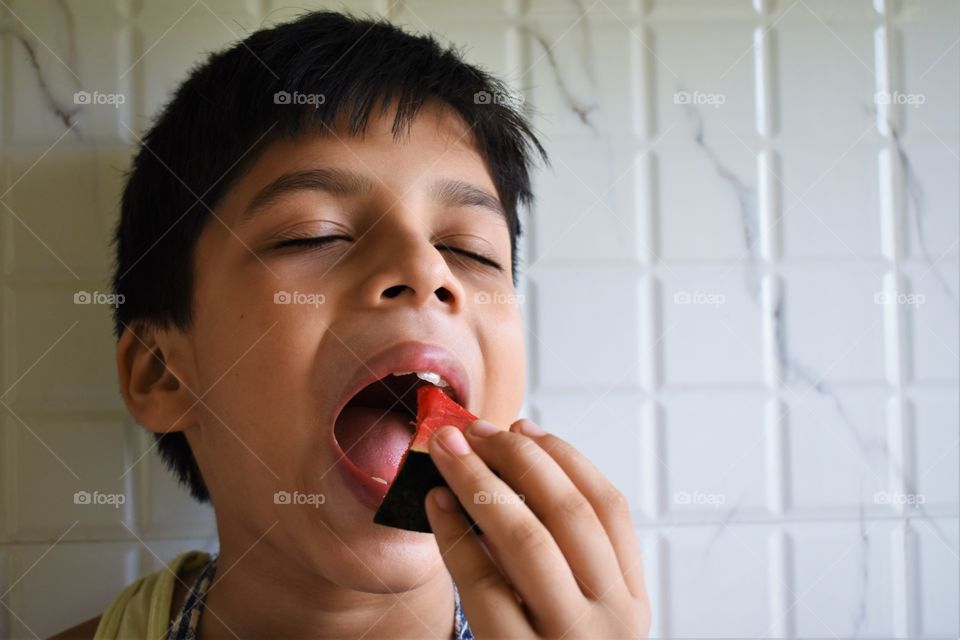 boy enjoying a piece of cool watermelon in summer