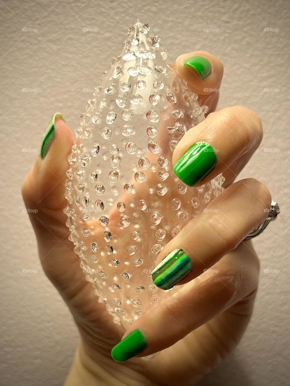 Hand with bright green nails holding a Christmas ornament 