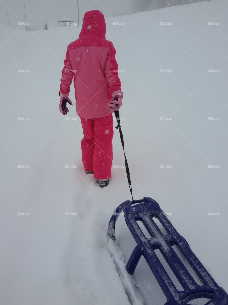 girl with a sledge in deep snow on mountain