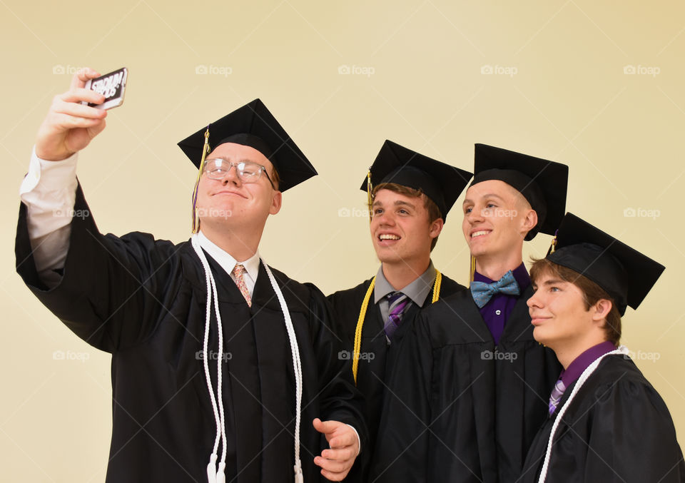 Graduates taking a selfie, wearing caps and gowns