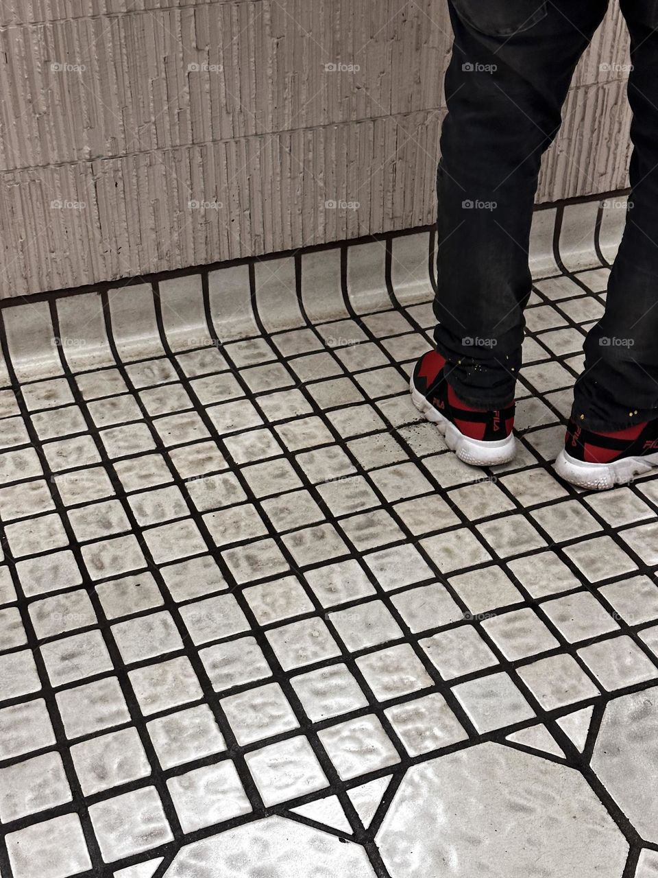 square off white commercial tile floor paired with thin ridged rough finish pinkish beige tiles in a bank showing partial image of person wearing dark denim and red athletic shoes