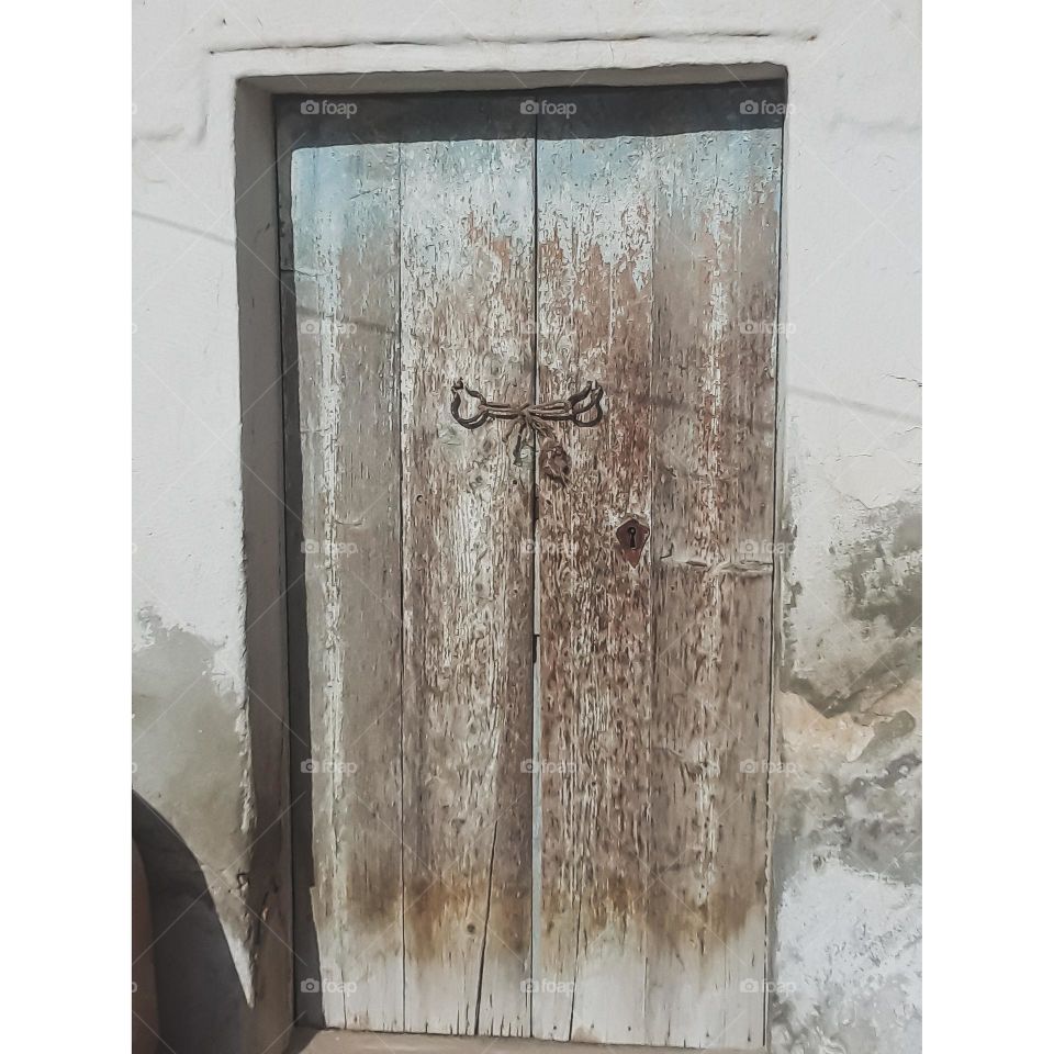 A wooden door that was affected by the factors of time, so old age appeared on it
It is the door to a room of a traditional house where the rooms are separated from each other and open to an open foyer