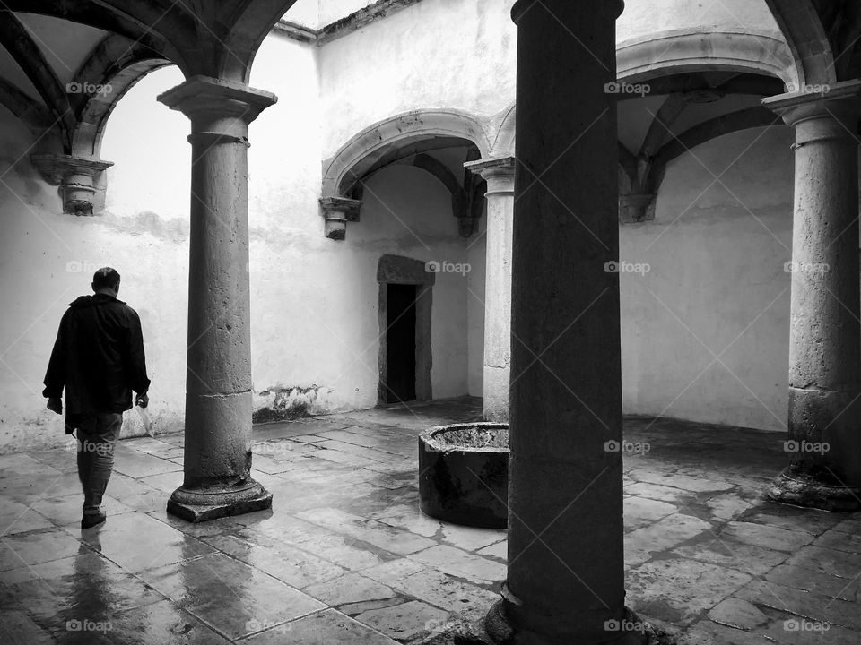 A man walks through an area of arches and pillars at Convento de Cristo, Tomar Portugal