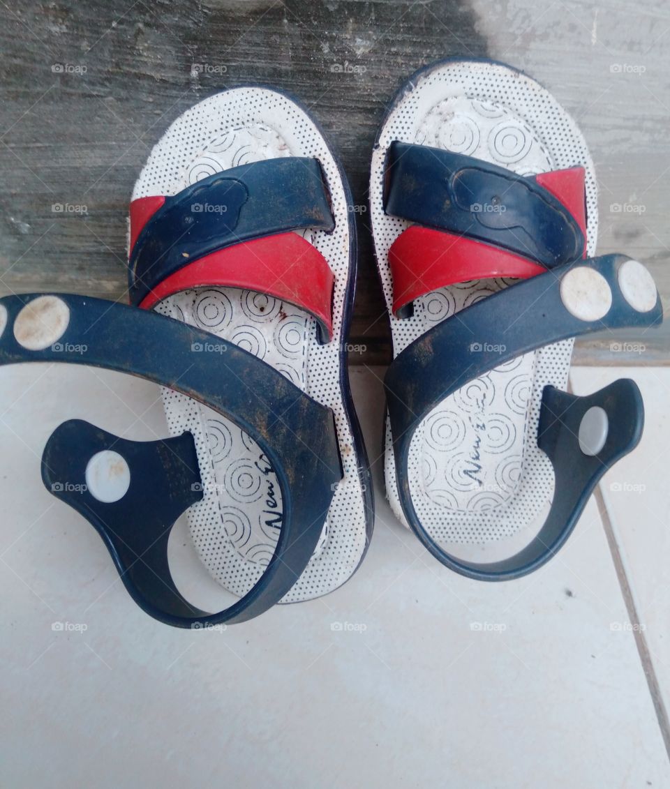 The slipper was leaning against the wall of the terrace of the house after being worn by a one year old child