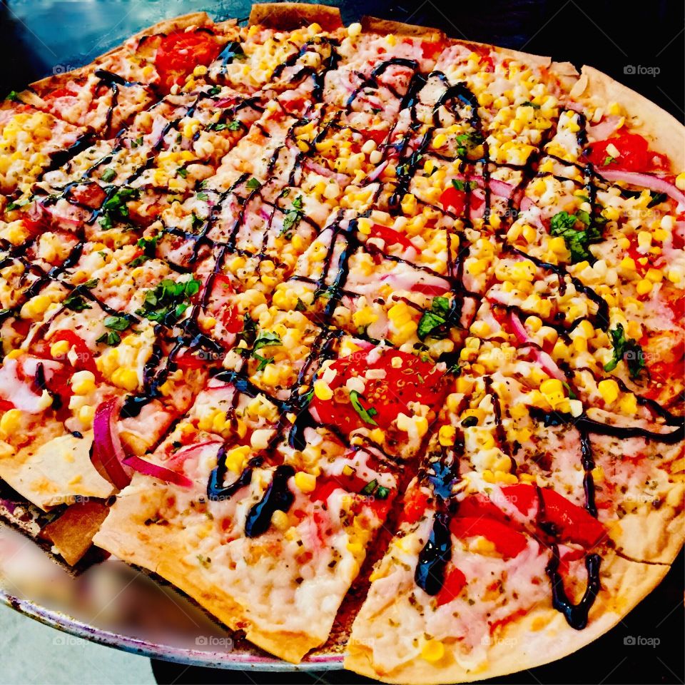 Mouthwatering handmade grilled pizza. Crafted with fresh, delicious ingredients including a tomato base covered with mozzarella cheese, corn, onions, tomatoes, basil and a balsamic drizzle to top it off. Yum!