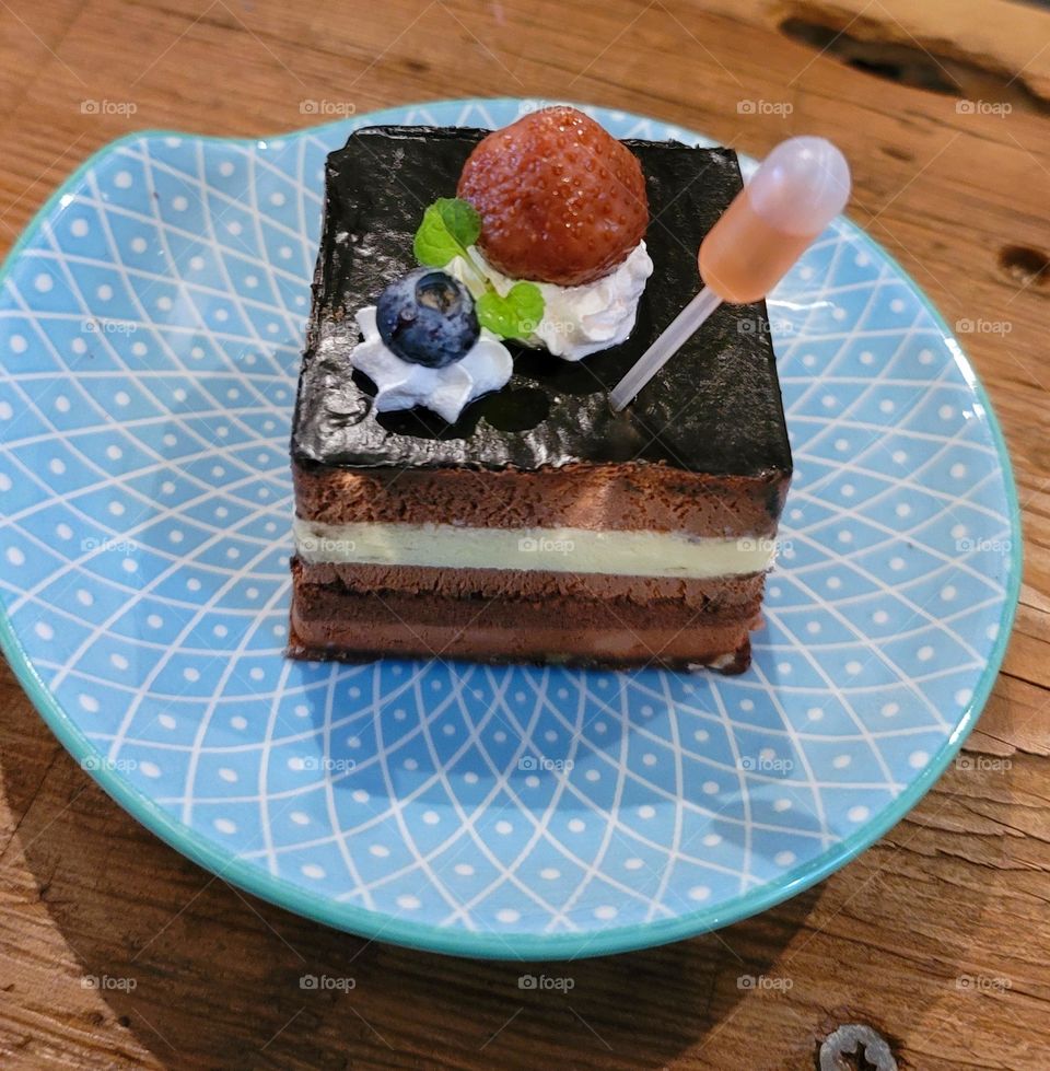 Chocolate cake with whipped cream, strawberries and blueberries paired with dropper wine