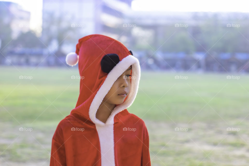 Asia boy wearing a red Christmas Background on the school lawn.
