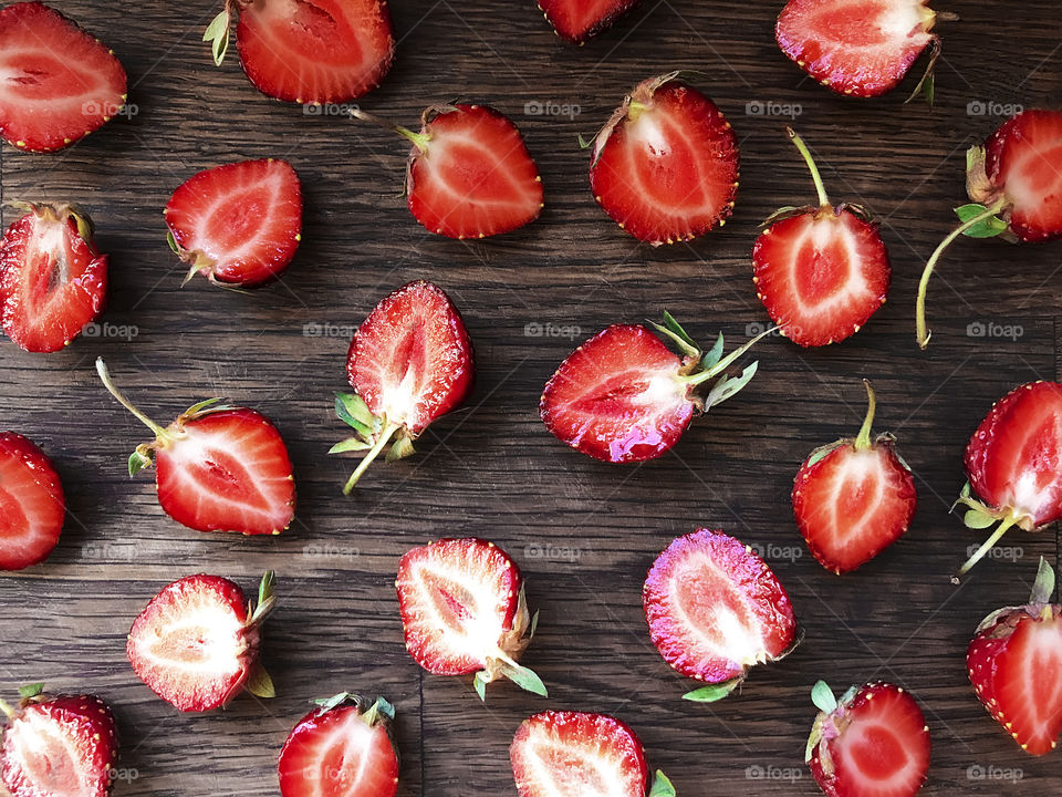 Simple pattern made of Slices of red ripe strawberries on rustic wooden background 