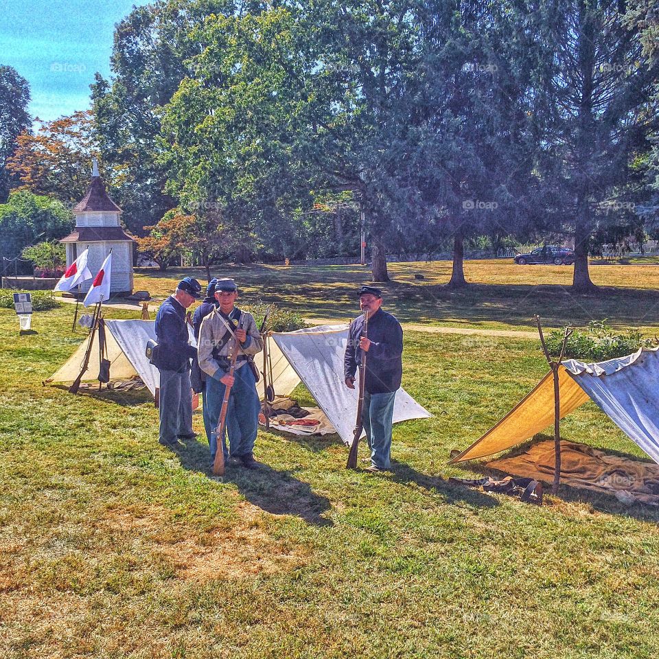 People standing in front of tent holding rifle in hand