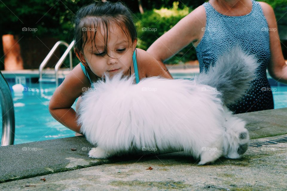 Little girl with dog at swimming pool