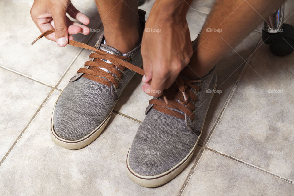 Young sportsman tying up tennis before going out to do running exercise in the morning