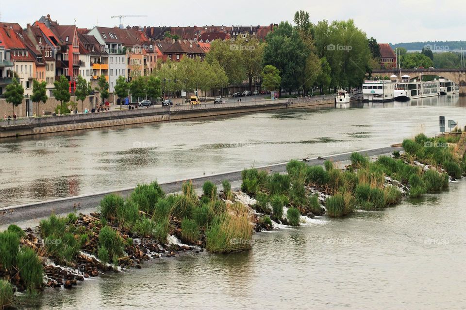 The river Main through the city of Würzburg with plants, ship and buildings 