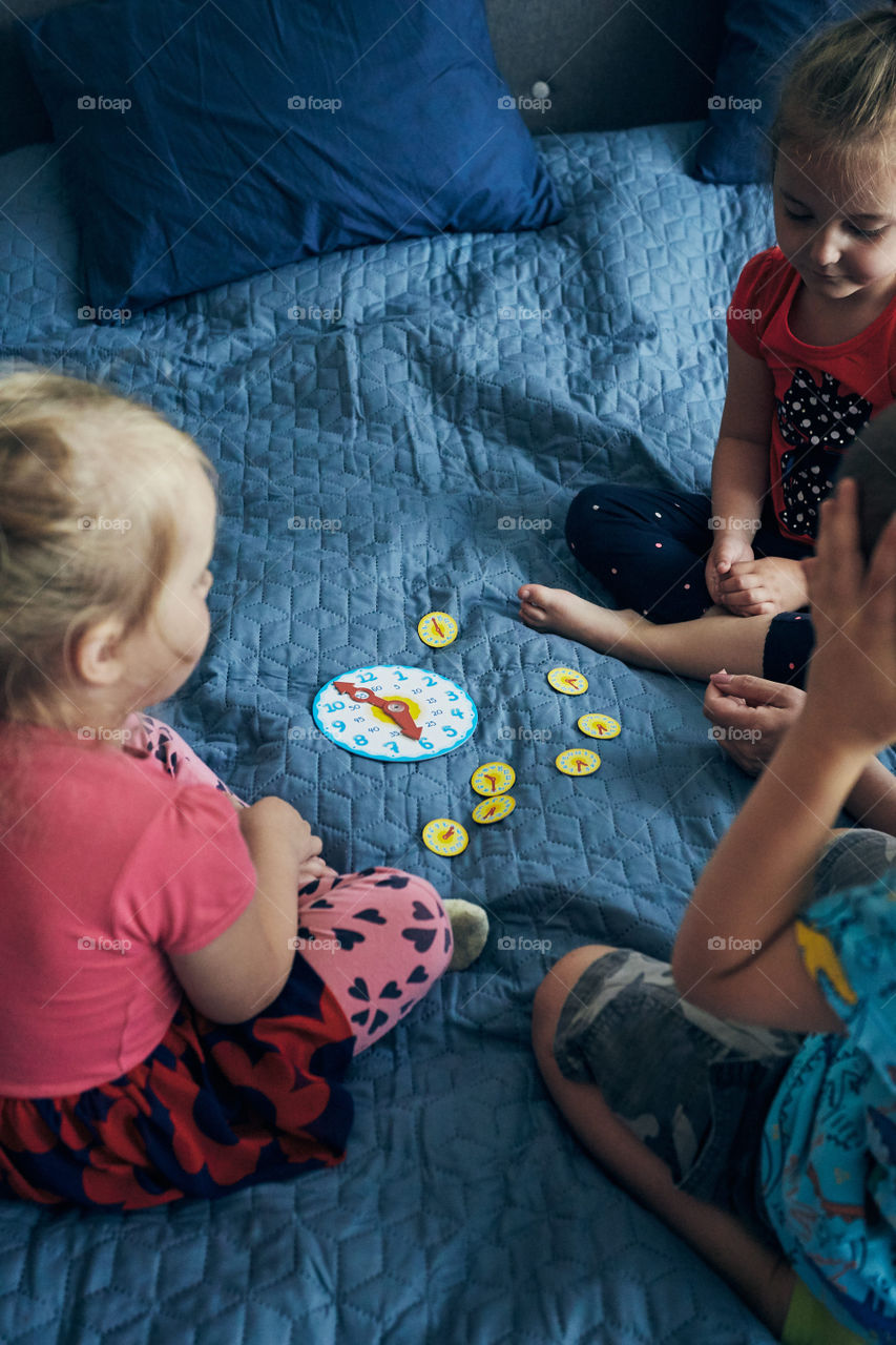 Kids learning how to tell time from clock and set the hands in the correct position. Teaching preschoolers tell time. Candid people, real moments, authentic situations