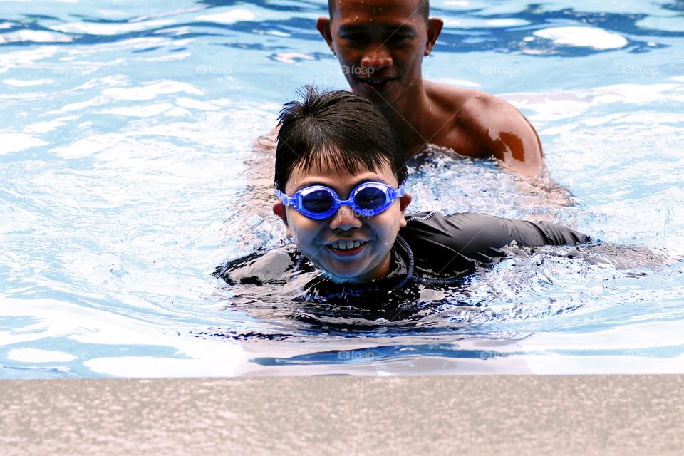 a swimming coach teaches a young boy to swim
