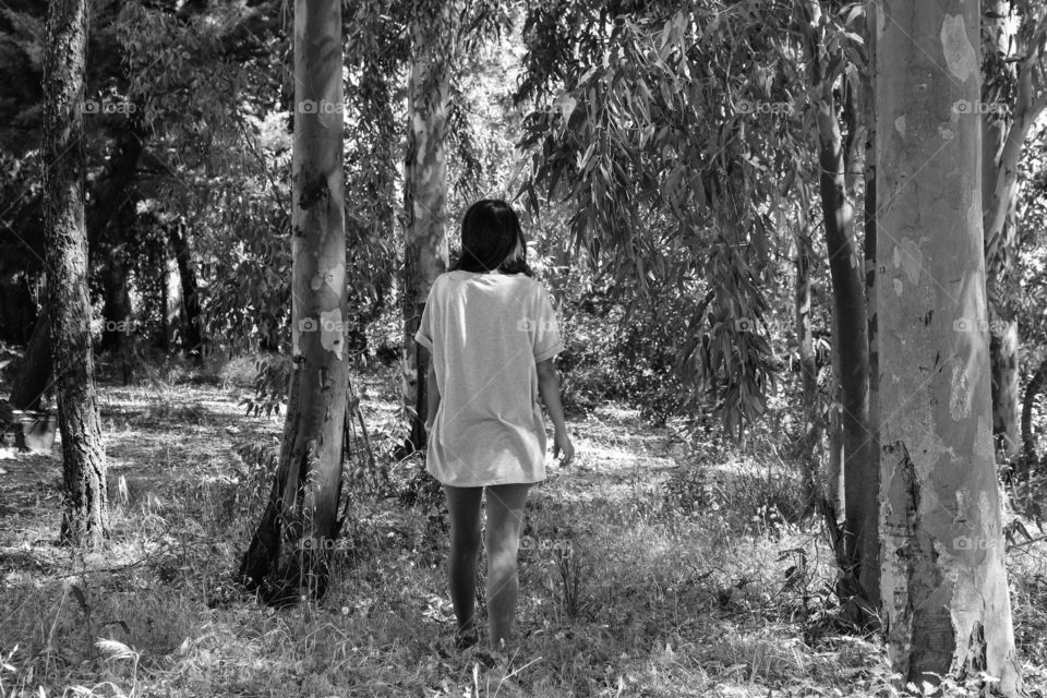 woman walking between trees