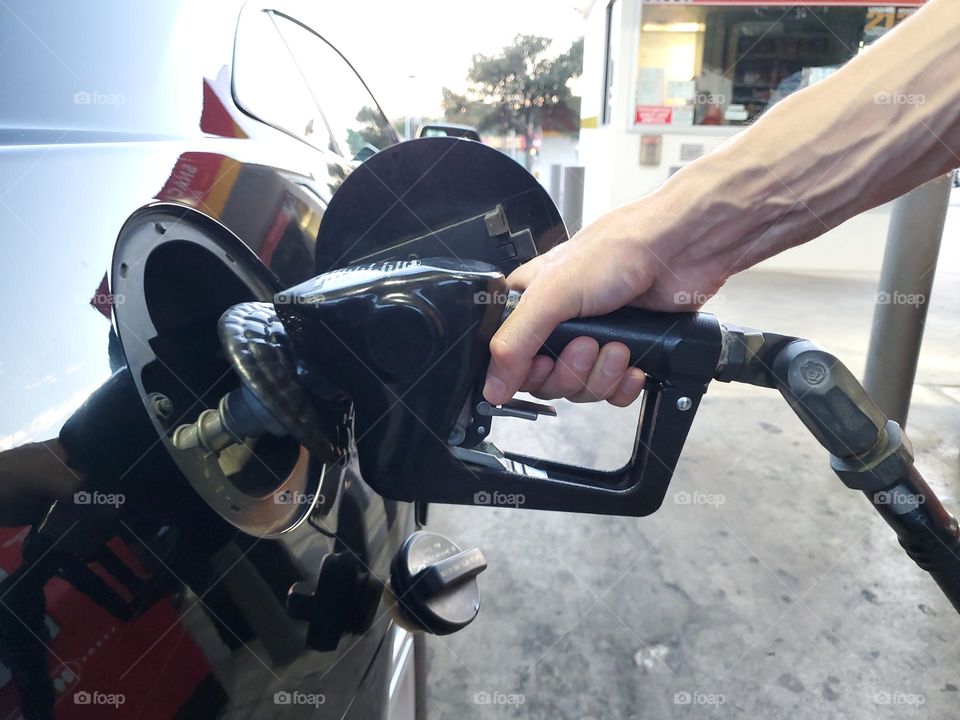 Closeup of a man filling his automobile gas tank at a gas station.