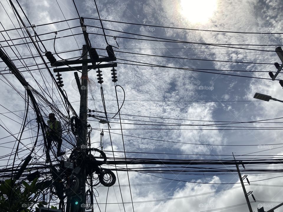 Thai government electrician is fixing the chaos electricity system upon the post without any safety tools at the intersection, Chalong, Muang, Phuket, Thailand