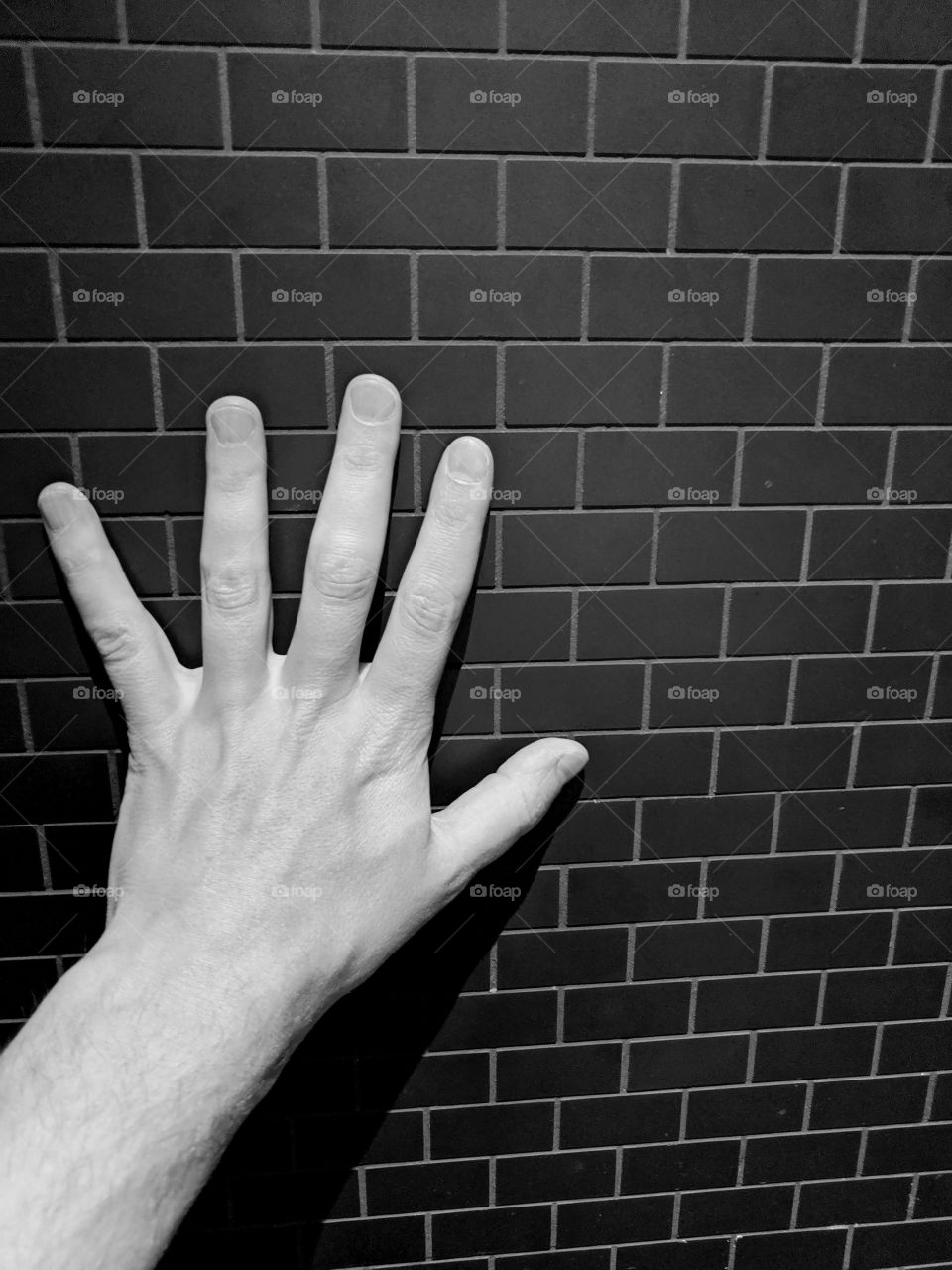 White hand against a black brick wall